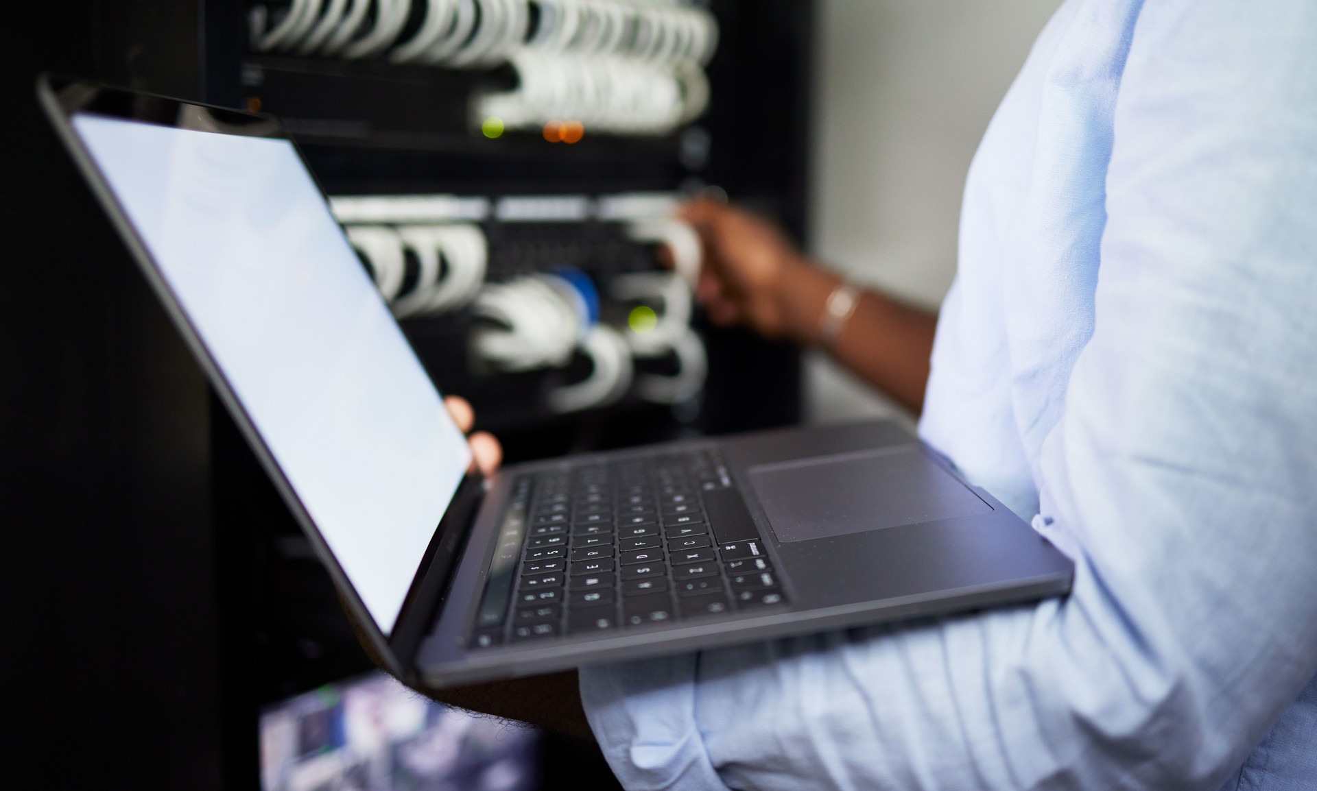 Server room, laptop and IT technician man with internet connection for software programming. Male engineer person with technology for cybersecurity, problem solving or system update in data center